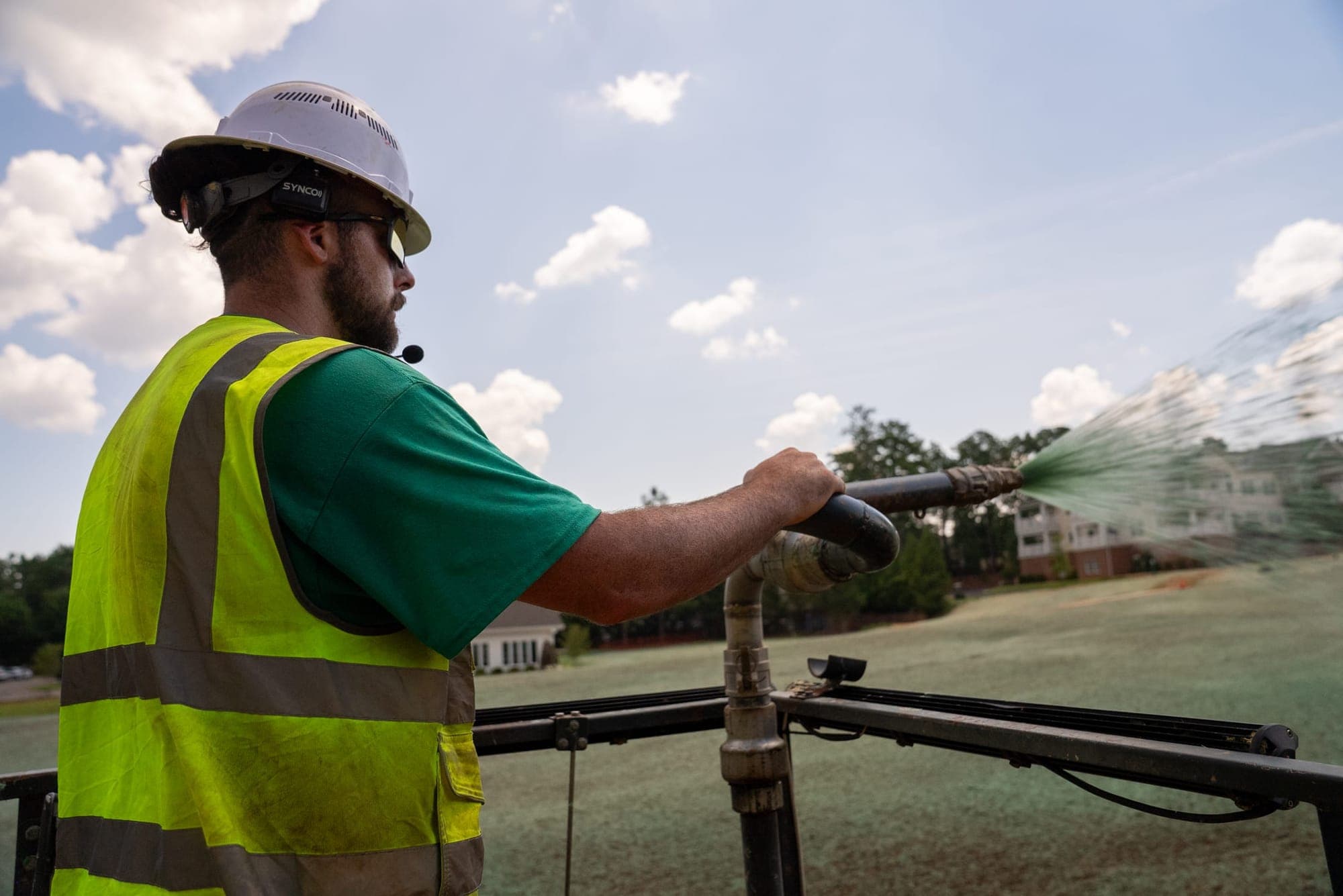 Prime Hydroseeding crew member applying hydroseed slurry across a commercial grading site