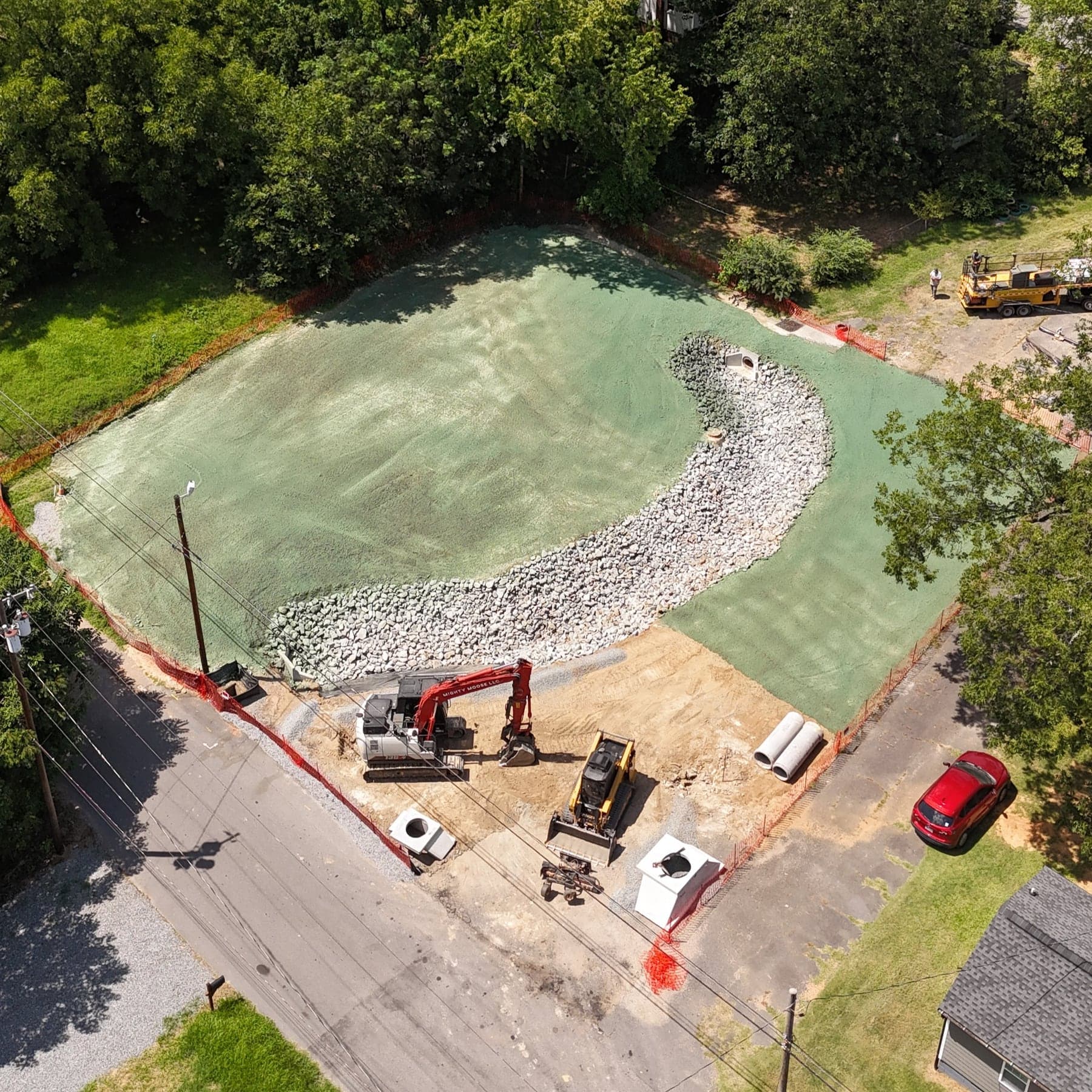 Aerial view of a hydroseeded stormwater basin with riprap channel and erosion control measures